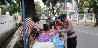 Personil Sat Brimob Polda Sumut bagikan nasi bungkus kepada warga yang sedang menaikin becak barang di Jl. Wahid Hasyim Medan