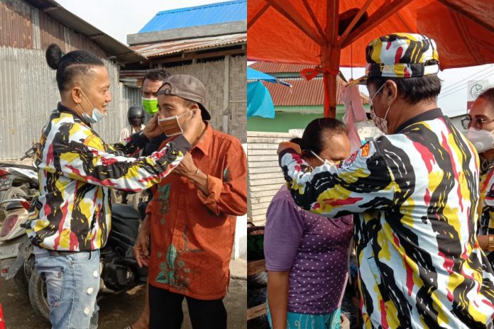 Ketua DPC PKN Deli Serdang Tumpal Sijabat terlihat memakaikan masker terhadap salah satu pedagang di TPI Pantai Labu, Sabtu (12/6/2021)